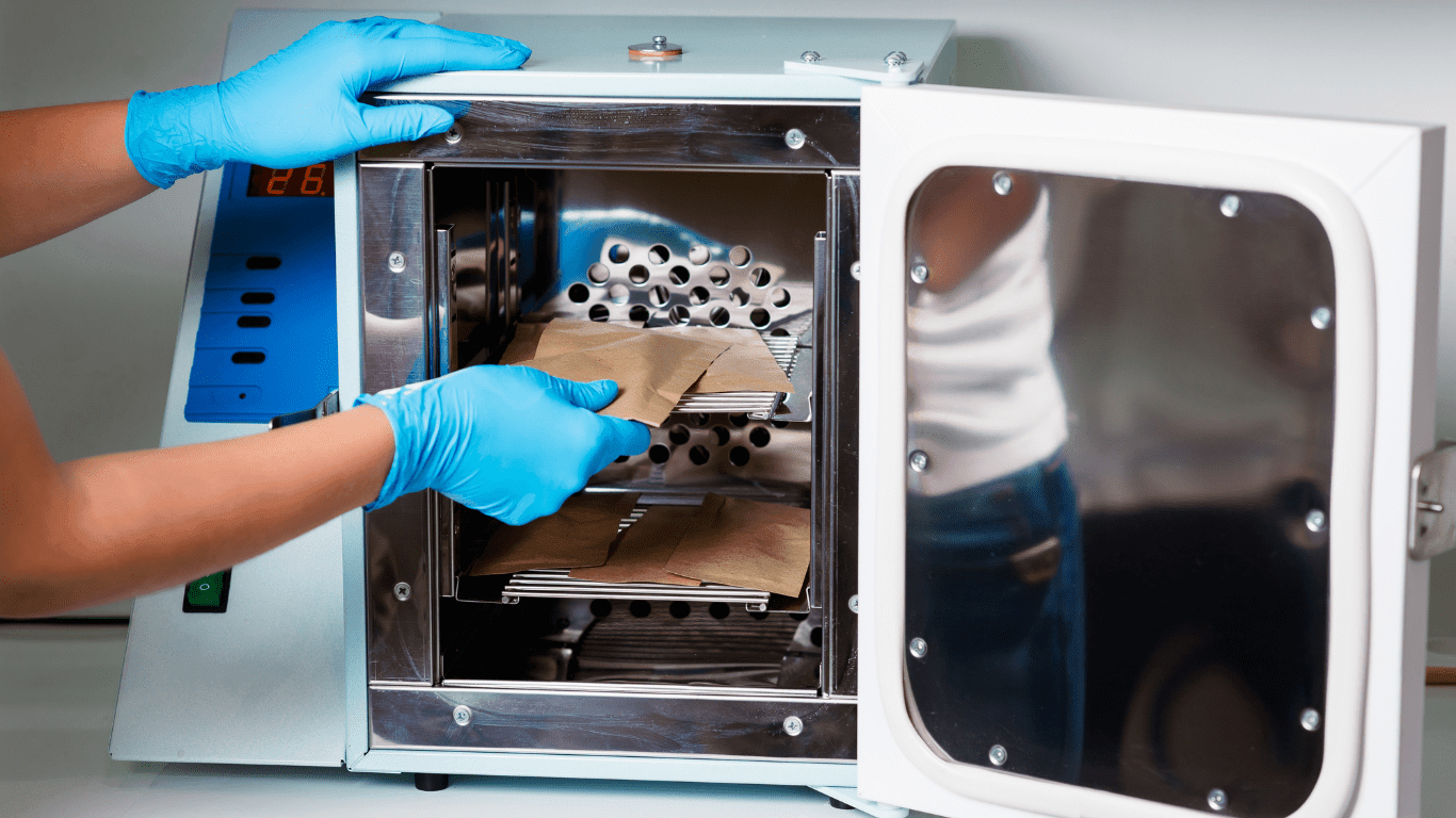 Gloved hands placing sterilization pouches in beauty salon autoclave machine