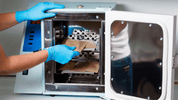 Gloved hands placing sterilization pouches in beauty salon autoclave machine