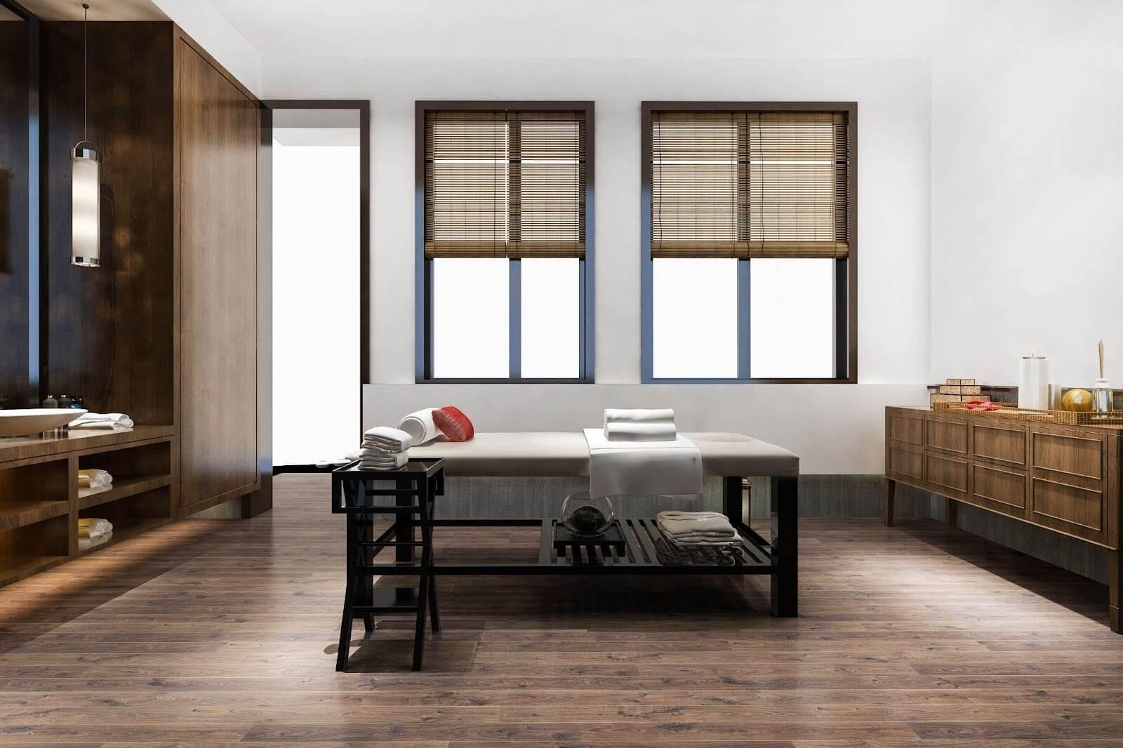 Modern beauty salon room with massage table, wooden furniture, and folded towels