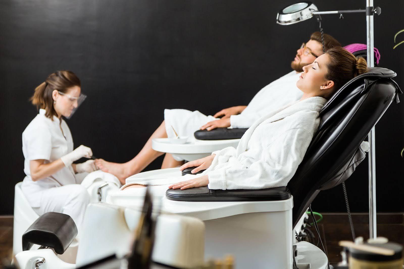 Modern beauty salon with comfortable pedicure chairs and clients receiving spa treatments